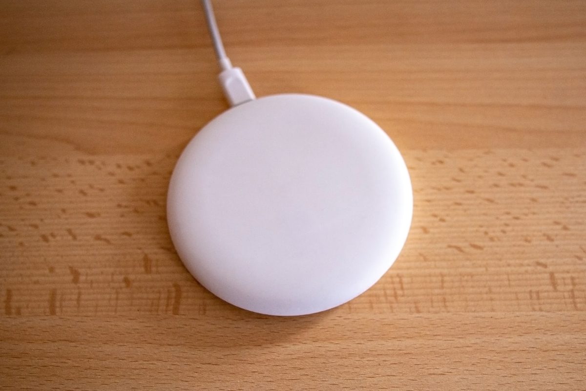 White round wireless charging pad with cable on a wood desk