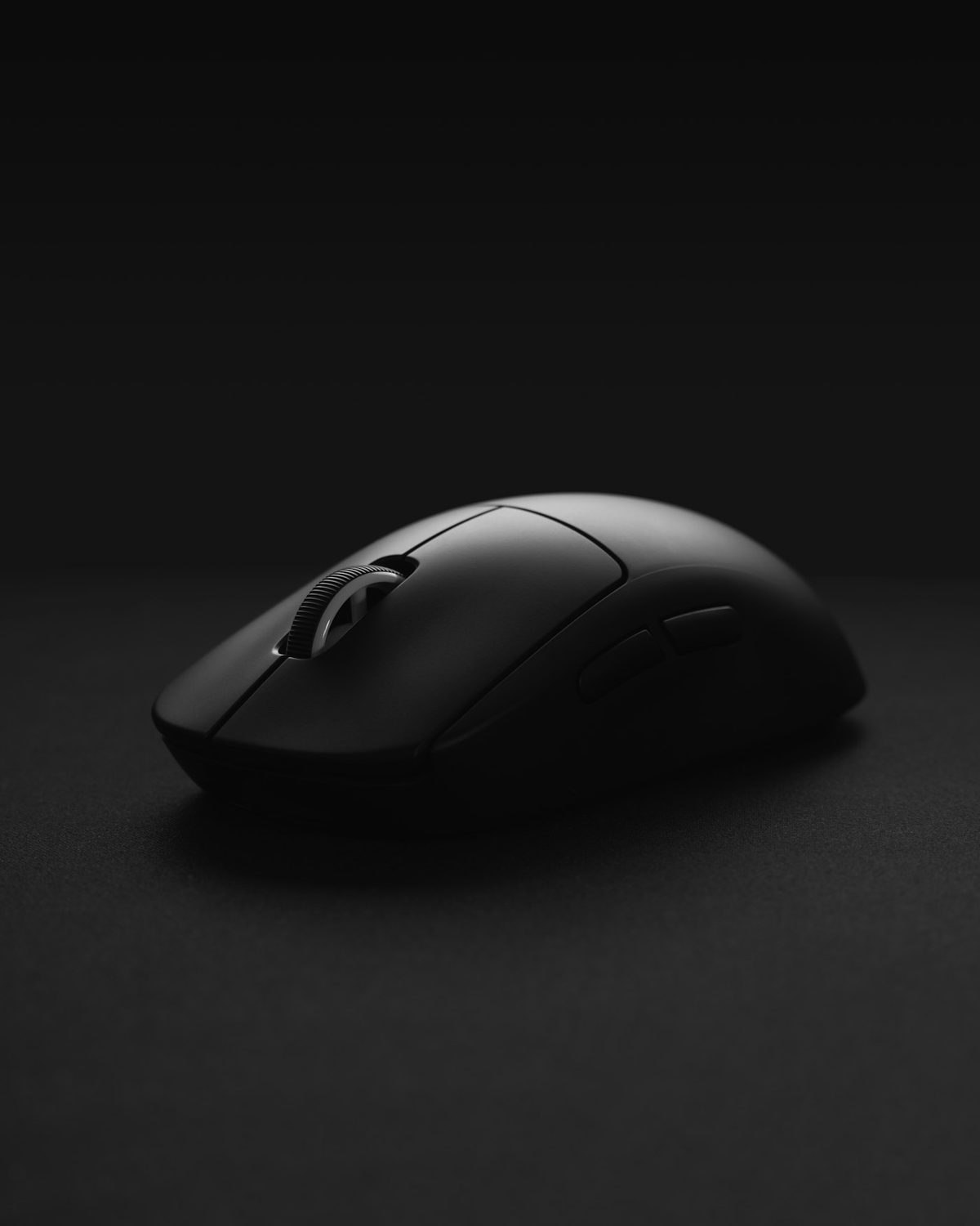 Black wireless gaming mouse lit dramatically on a dark surface