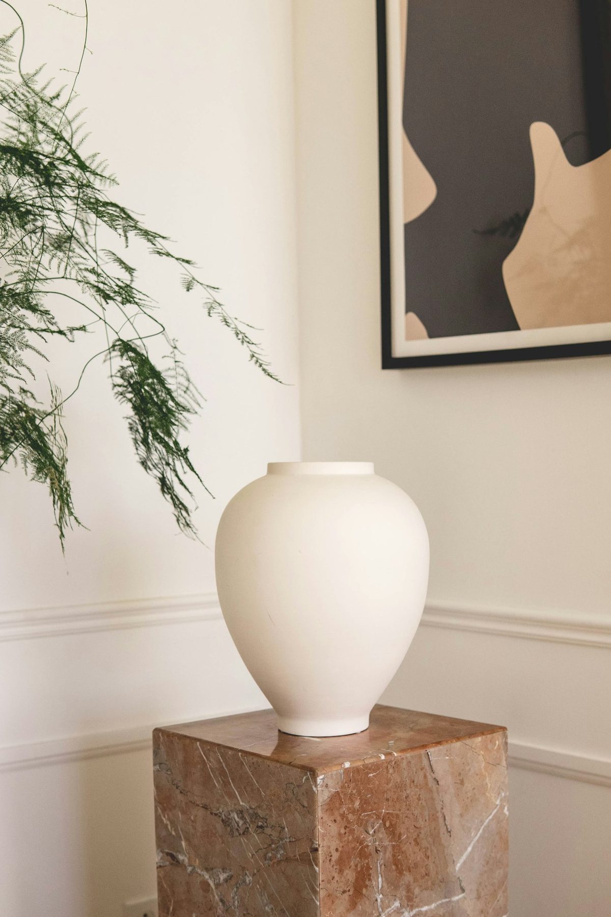 Cream matte ceramic vase on a marble plinth